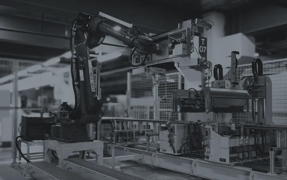 Robotic cell on a plant floor: six-axis industrial arm over a transfer line.